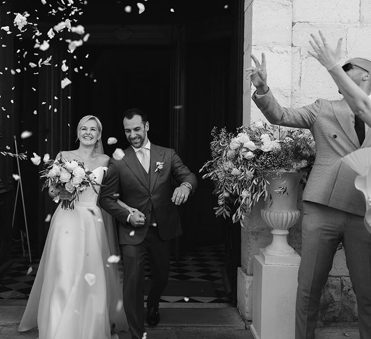 Bride & groom walk through confetti after church wedding ceremony in France