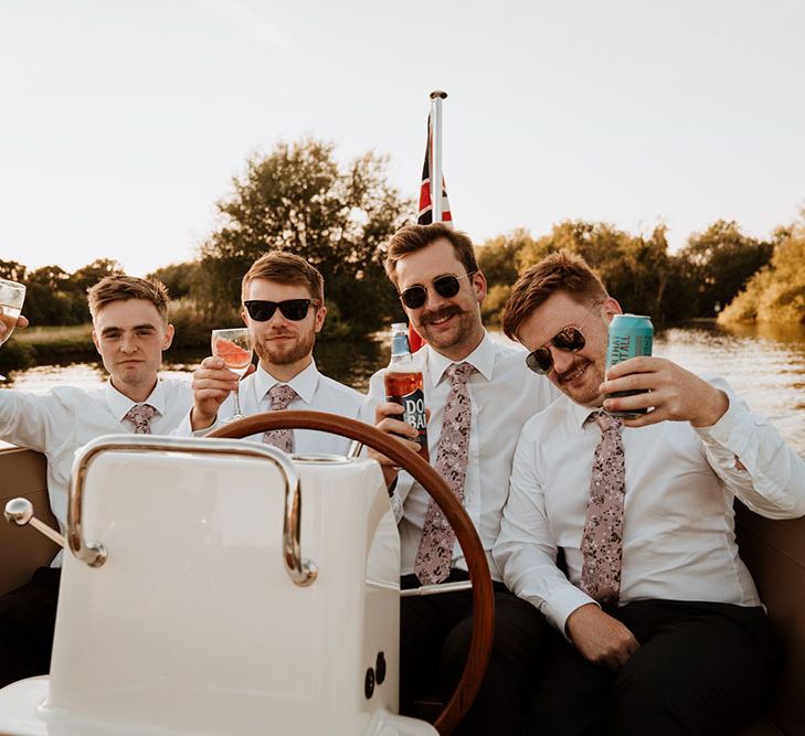 Groom sits with his groomsmen wearing sunglasses on riverboat 