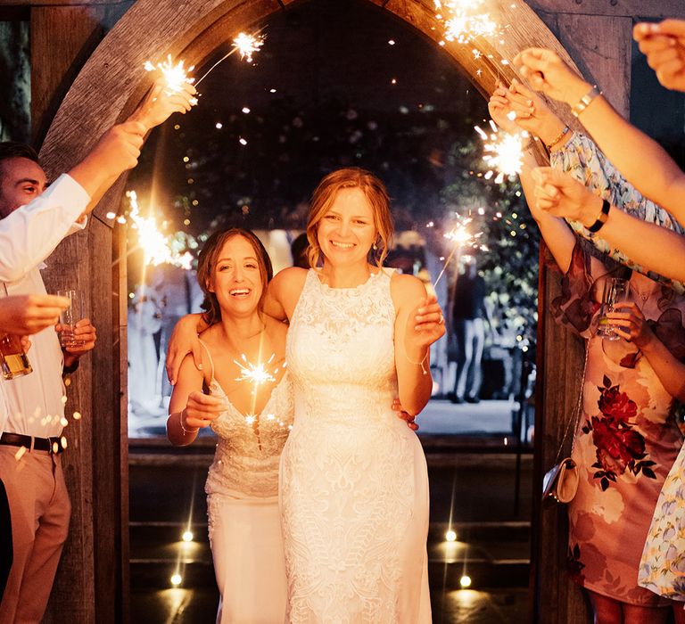 Brides have a sparkler send off from their outdoor summer wedding 