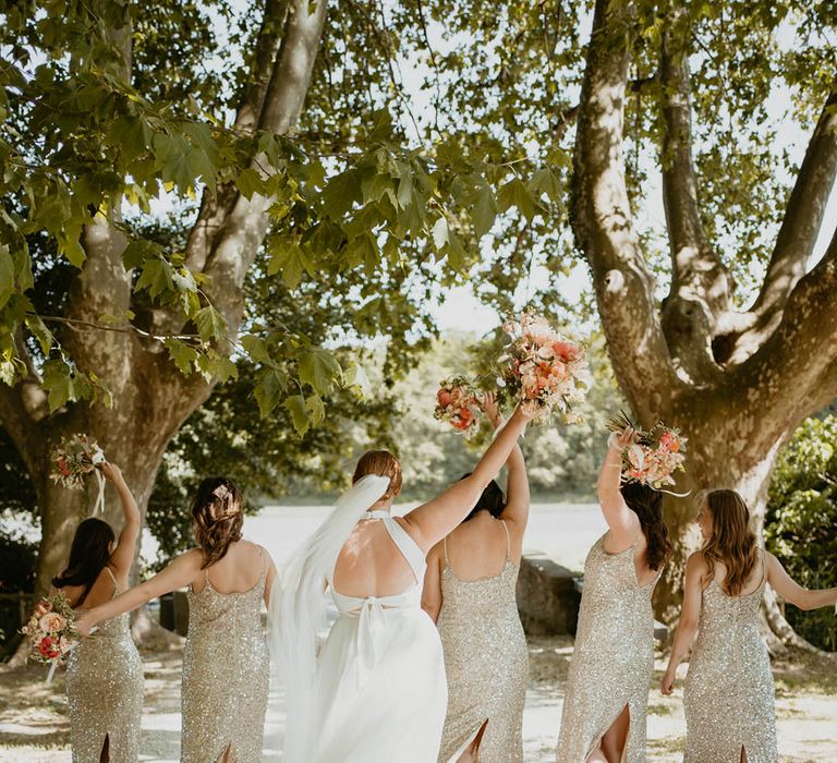 Bridesmaids in gold sequin dresses with the bride in a halter tie wedding dress for a destination wedding 