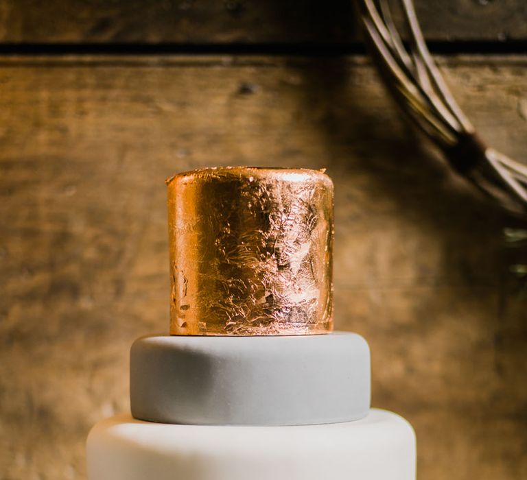 Plain iced white and grey wedding cake with a metallic rose gold iced layer for a winter wedding 