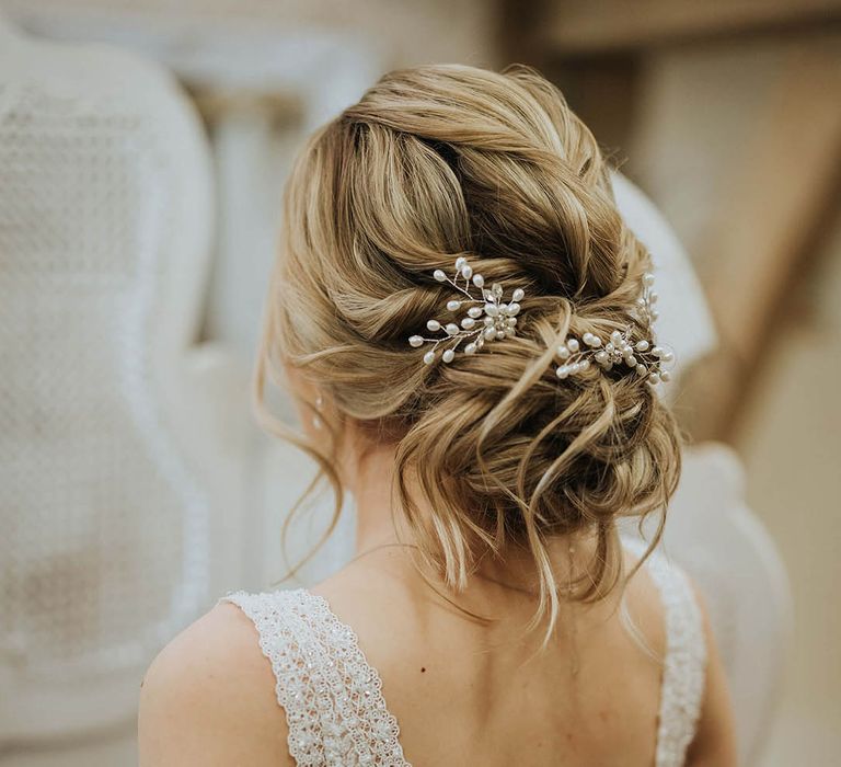 Bride with blonde hair in an updo with a pearl and silver floral wedding hair accessories