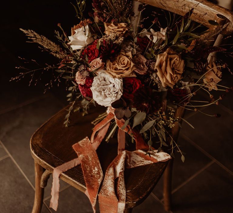 White, red, and toffee coloured rose autumnal wedding bouquet tied with a velvet ribbon 