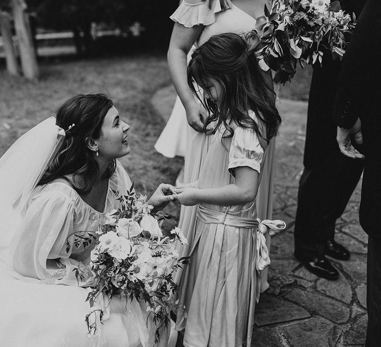 Bride in a strapless wedding dress with a balloon sleeve sheer overlay greeting a young wedding guest 