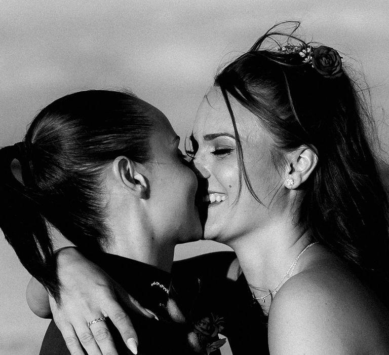 Brides laugh as they kiss 