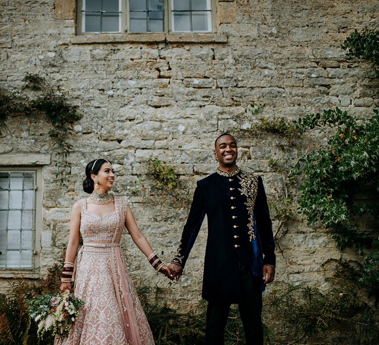 Bride and Groom hold hands in front of country wedding venue