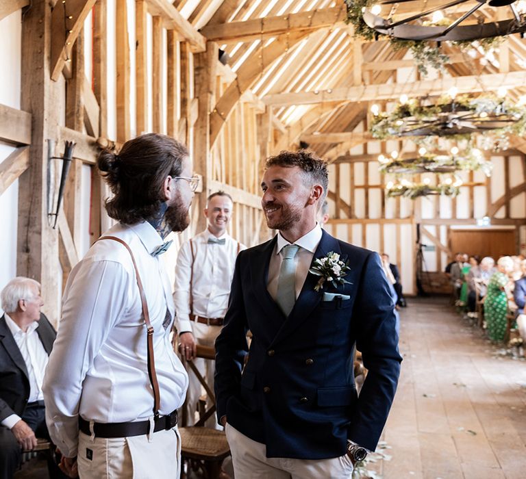 Groom wears fitted blue jacket with pale blue tie and white floral buttonhole 