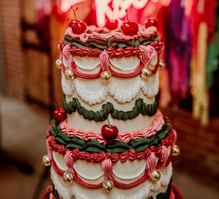 Retro wedding cake with three tiers and pink, purple and green frosting, cherries and disco ball decorations 