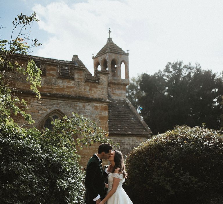 The bride and groom share an intimate kiss as they share a moment alone together for their classic and timeless wedding 