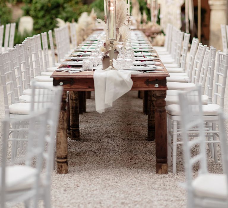 Wooden banquet tables complete with candles and pampas grass decor 