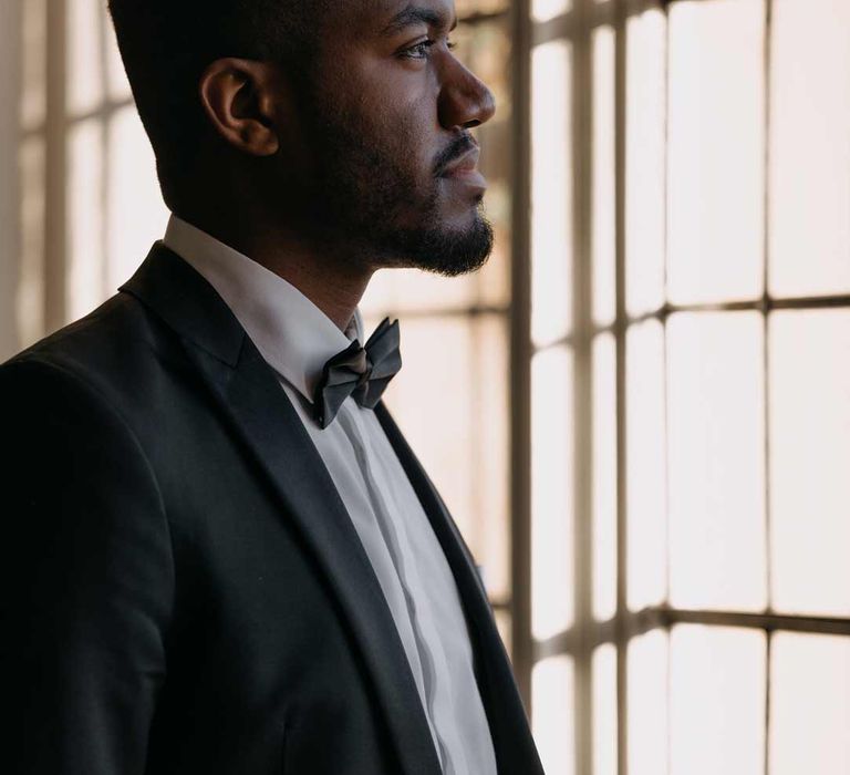 Groom in classic three piece black tuxedo, black bowtie and white pocket square