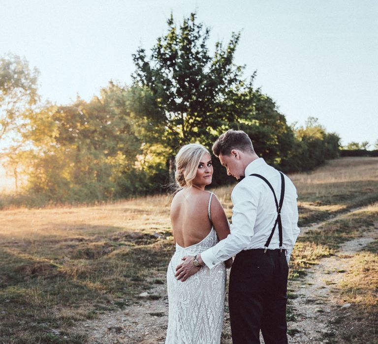 Bride in backless Galia Lahav mermaid style wedding dress walking with the groom 