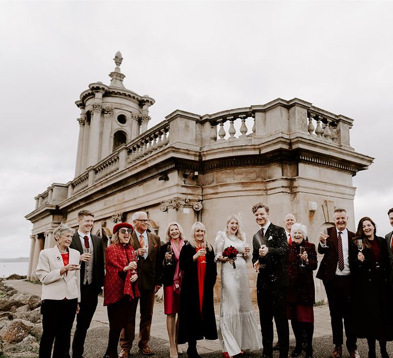 The wedding party pops champagne in front of the Normanton Church 