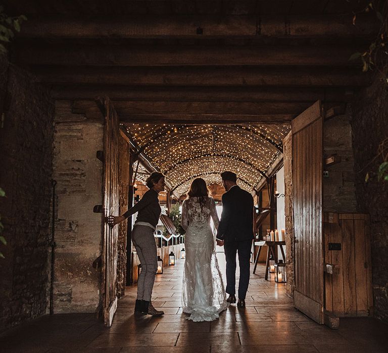 Bride in lace winter wedding dress and groom in navy suit walk out of their civil ceremony together 