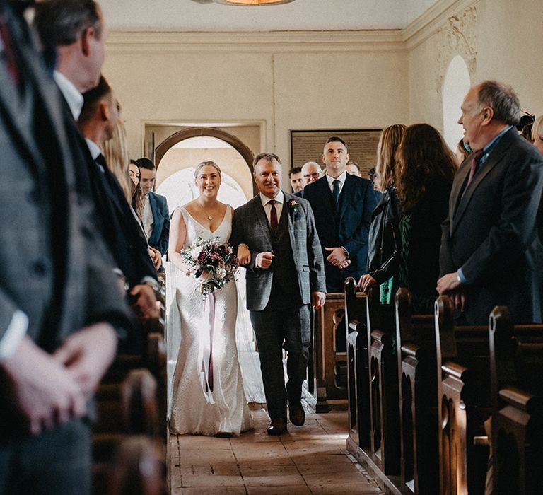 Bride and father of the bride walking down the aisle together for the church ceremony 