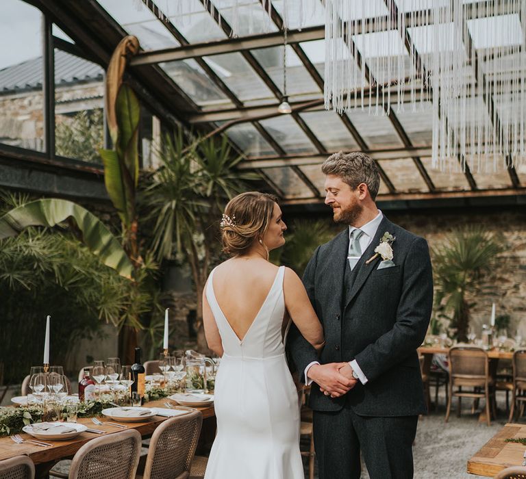 Anran Devon wedding venue glass house with the bride and groom standing next to their wedding breakfast tables