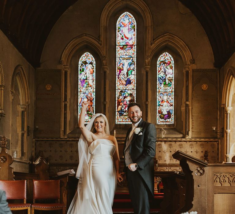 Classic church wedding with the bride wearing a strapless Eva Lendel wedding dress and groom in a black and grey suit 