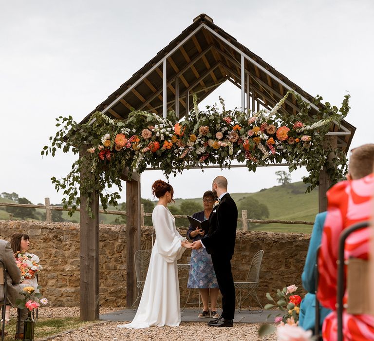 Orange and red wedding flower installation decorating the outdoor wedding 