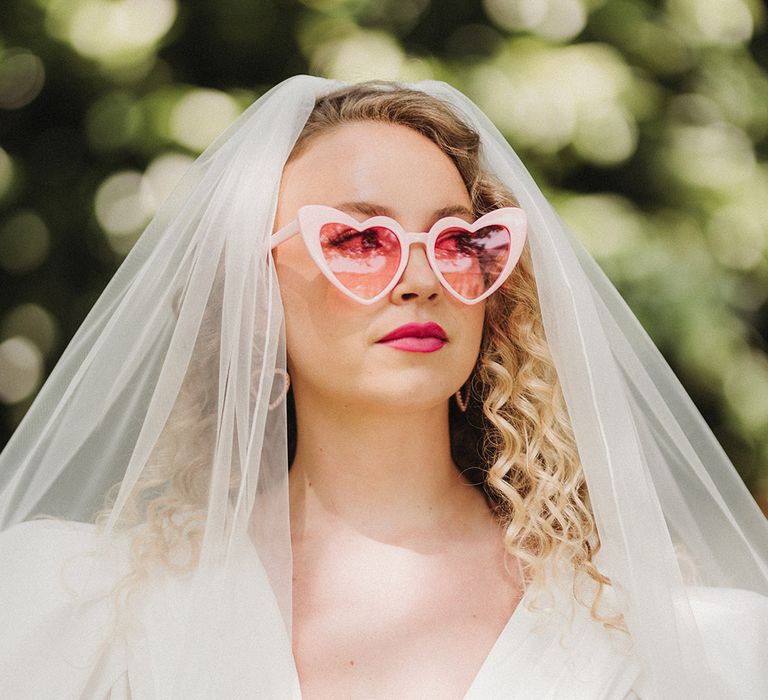 Bride in puff sleeve wedding dress with pastel pink retro sunglasses bridal accessories for pink theme wedding 