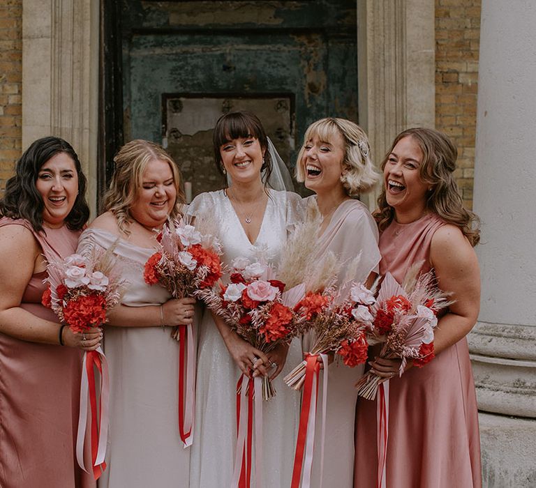 Bridal party in mismatched pink bridesmaid dresses with preserved wedding flower bouquet 