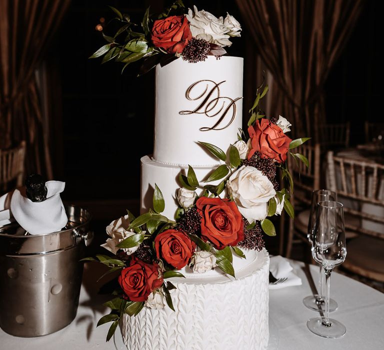 Luxe three tier white iced wedding cake with red rose flower decoration and personalised initial decorations 