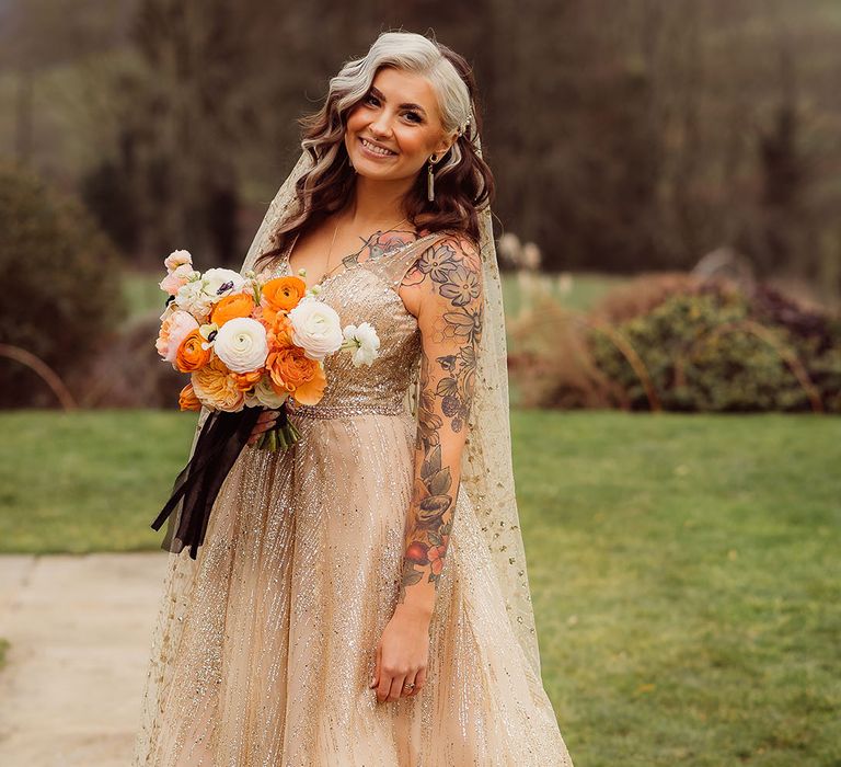 Bride in sparkling gold autumn wedding dress with autumnal bouquet for fall wedding 