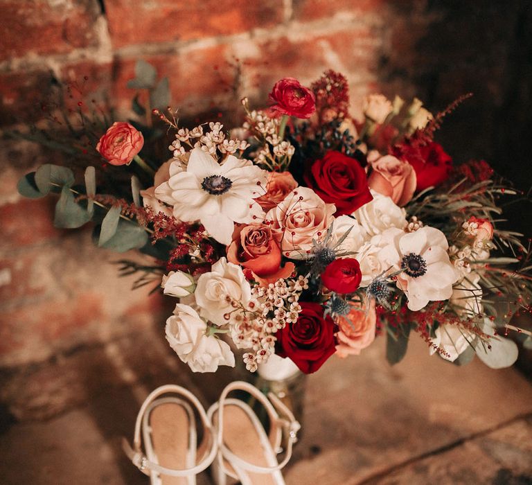 Sparkly white wedding shoes with red and white wedding bouquet with white anemones 