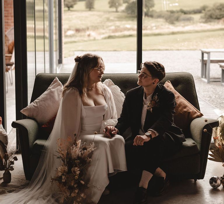 Bride in elegant long sleeve wedding dress sitting with the birde in a brown suit from ASOS 