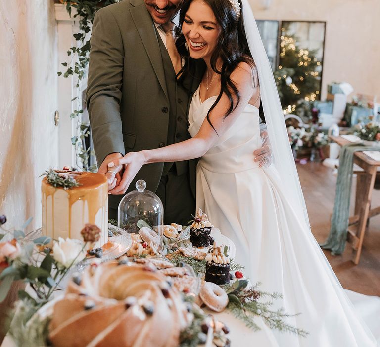 The bride and groom cut their wedding cake on their dessert table 