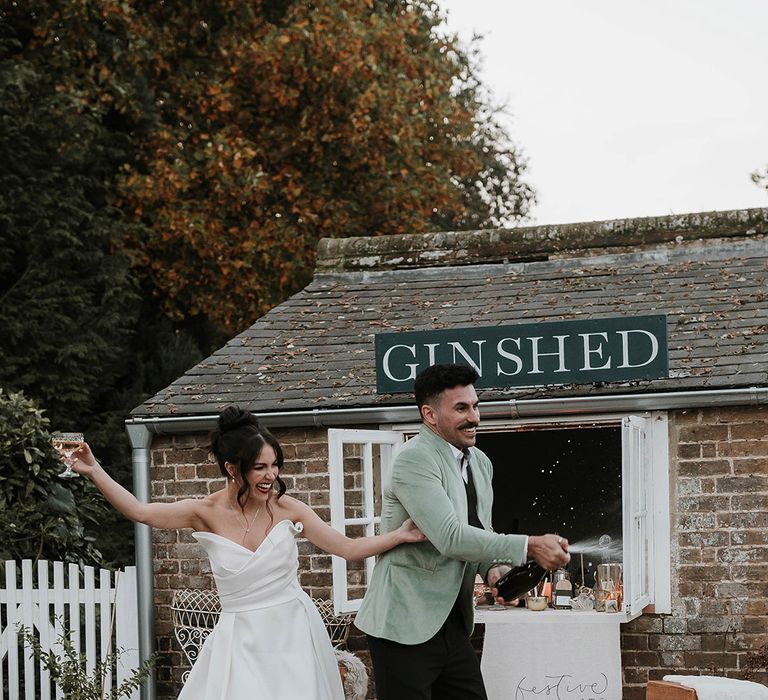 Fun champagne popping moment for bride and groom outside drinks wedding stationery 