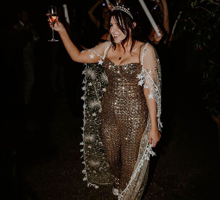 Bride in copper gold jumpsuit with lace sheer cape and star crown accessory 