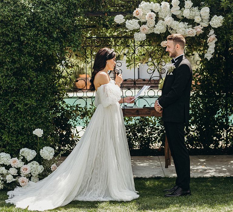 Bride in princess off the shoulder wedding dress with groom at outdoor wedding venue 