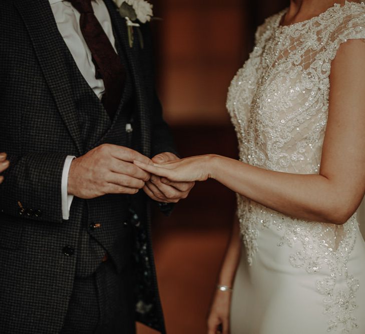 Bride and groom exchanging of rings at Lake District wedding with stunning sequin embellished Morilee wedding gown