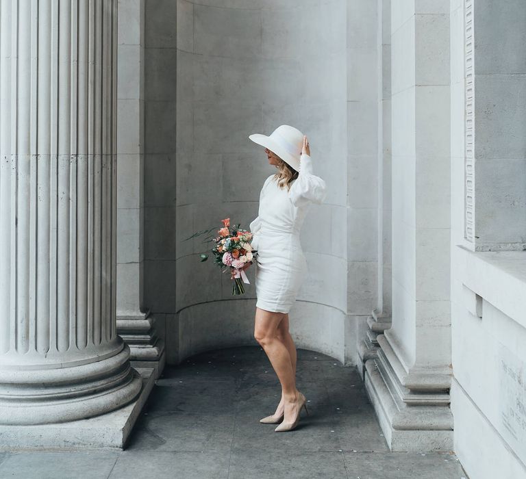 Bride wearing short wedding dress and white wedding hat for London wedding