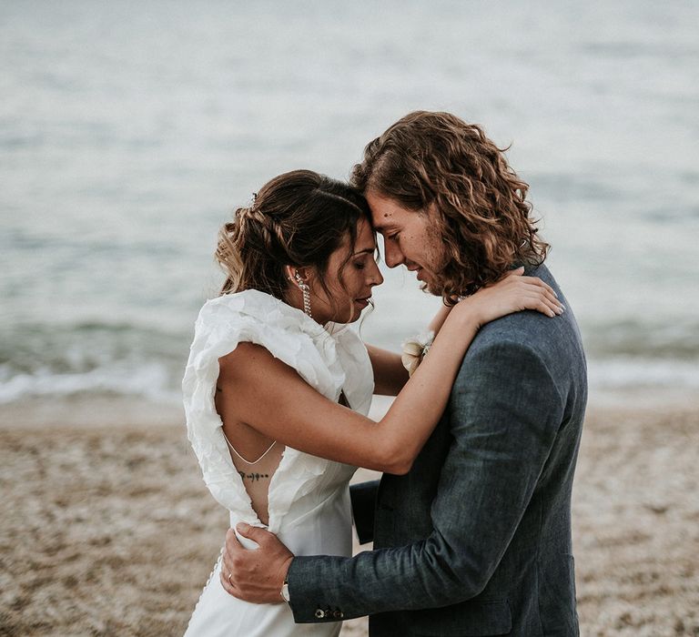 Bride in Rime Arodaky wedding dress with sheer panel side detail and ruffle sleeves on the beach with her husband in Italy 