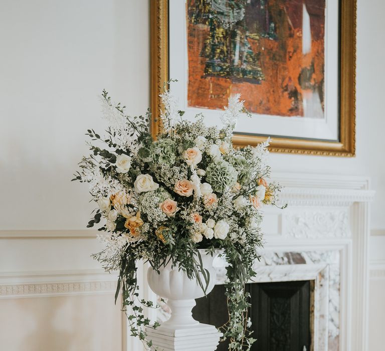 Peach and cream wedding flower arrangement on a plinth