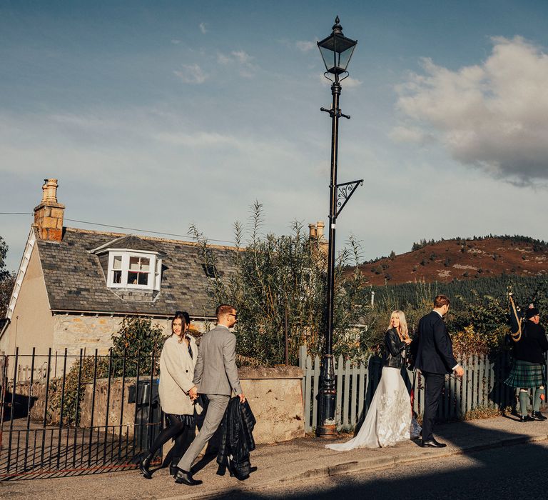 Bride & groom walk with wedding guests in Scotland