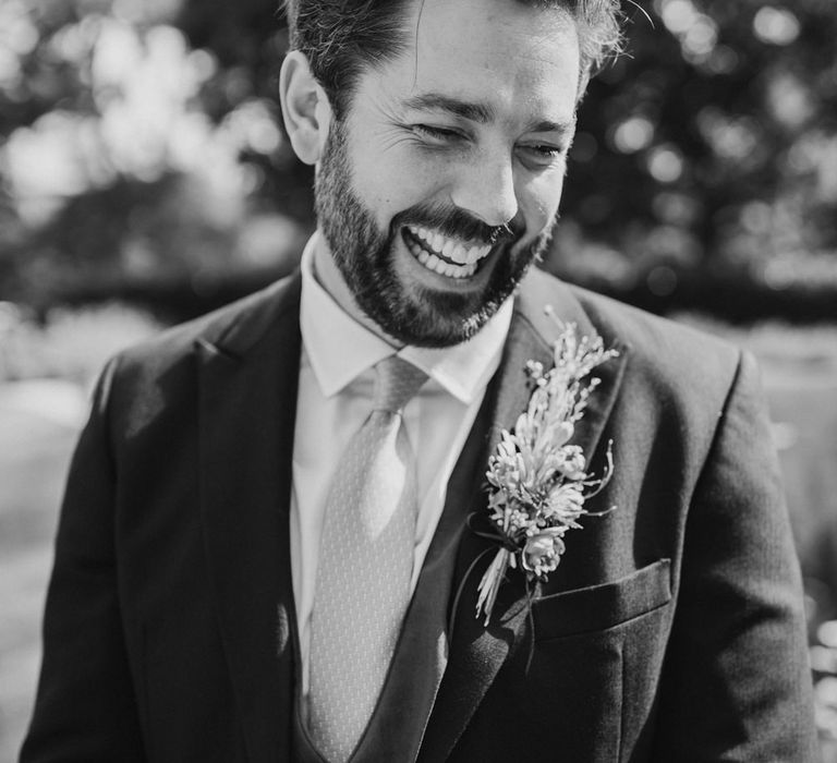 Black and white portrait of a bearded groom laughing in a morning suit