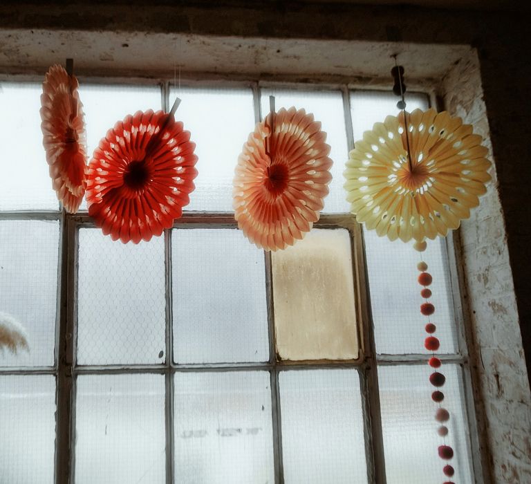 Colourful pin wheel wedding decor hanging up at a window 