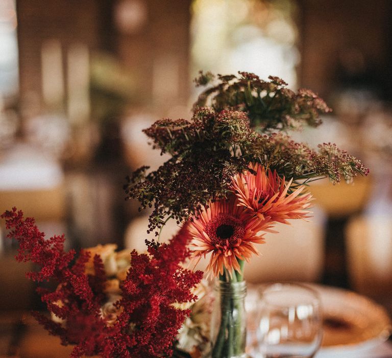 Red gerbera flower stems in bottles as wedding centrepieces 