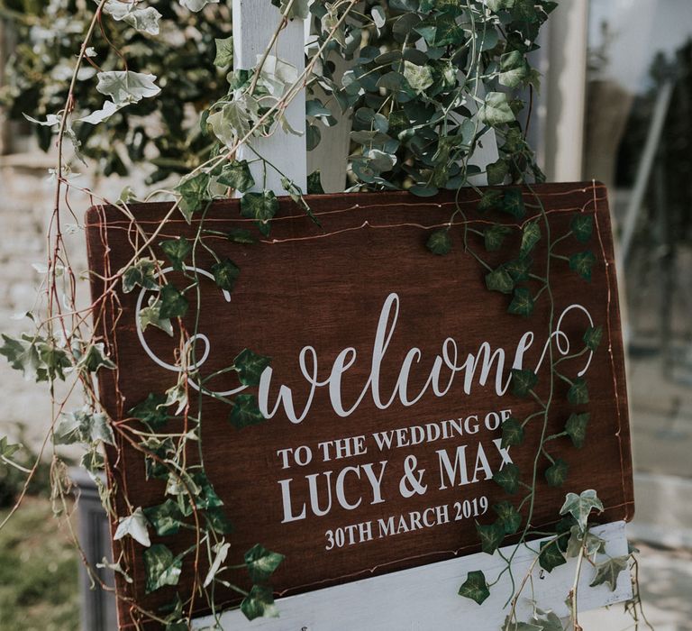 Rustic wooden wedding welcome sign with ivy foliage decor at Caswell House Wedding