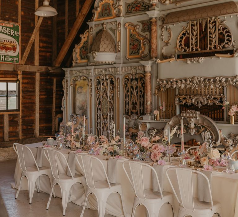 Pastel wedding theme tablescape with white industrial chairs, iridescent glassware, taper candles and floral centrepieces 