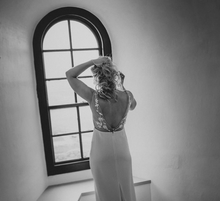 Bride stands in the window in black & white image on the morning of her wedding