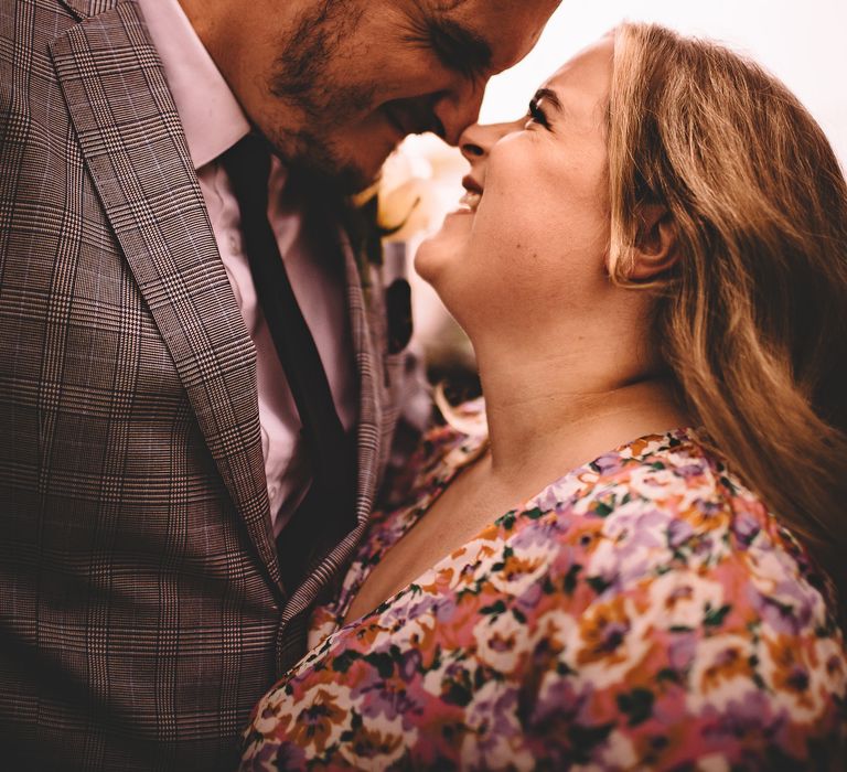 Bride & groom smile and laugh lovingly whilst looking at one another