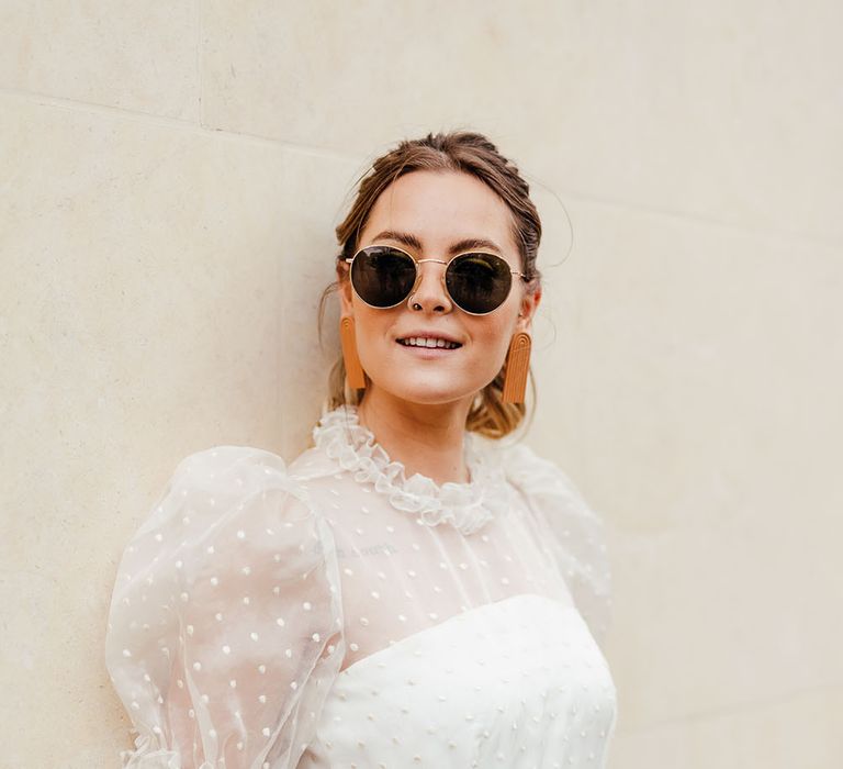 Stylish bride in a polka dot tulle wedding dress with puff sleeves, and round sunglasses 