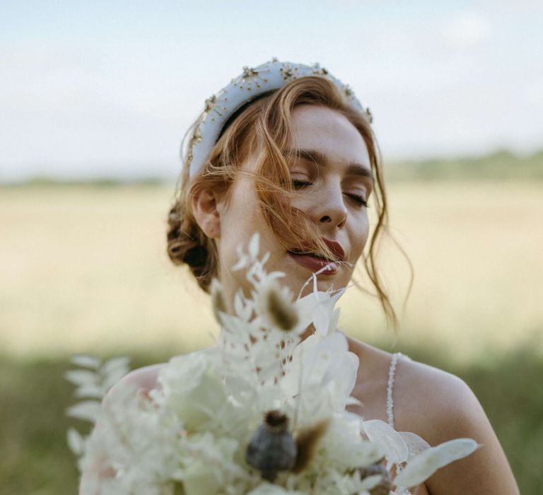 Bride wearing a white and gold beaded headband with all white flower bouquet