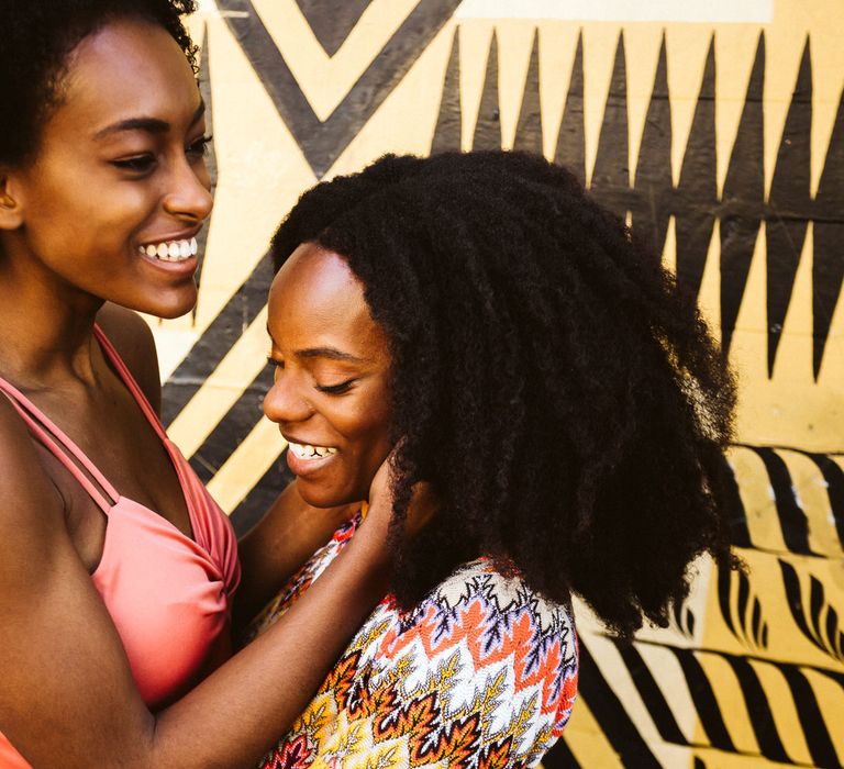 LGBTQ+ Black bride with short afro hair embracing her brides face during engagement photoshoot 