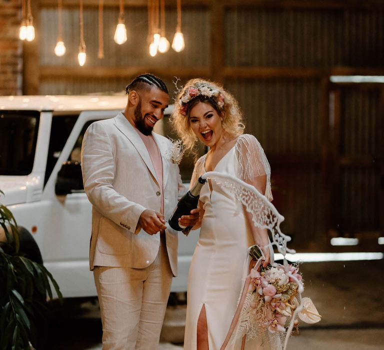 Bride and groom spraying a bottle of champagne