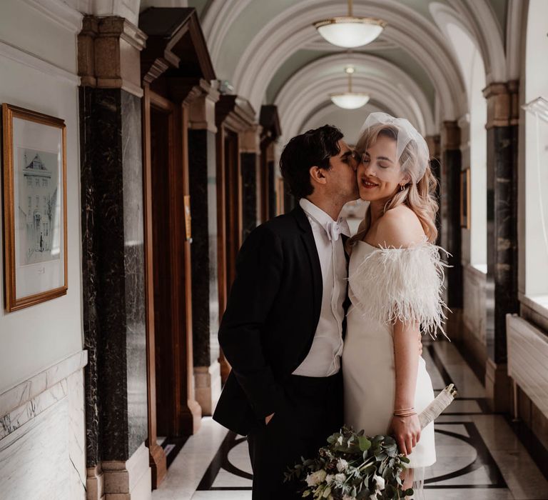 Groom kissing his wife on the cheek