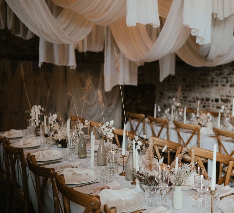 elegant place settings with ornate tableware, gold rimmed glassware and neutral floral centrepiece decor 